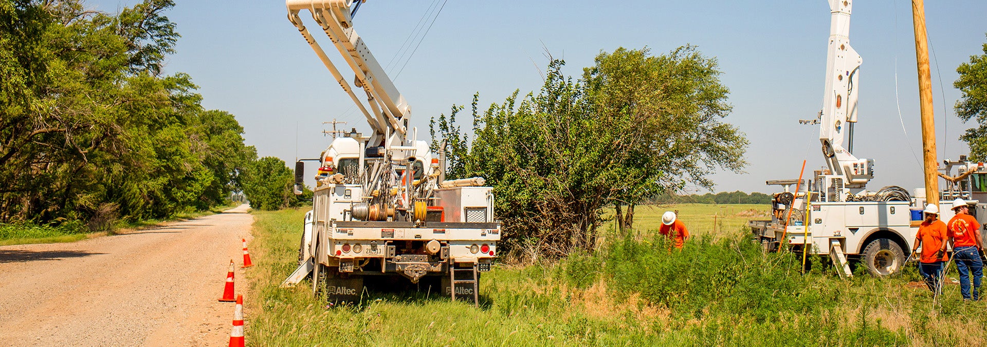 Electric utility trucks at the side of a dirt road