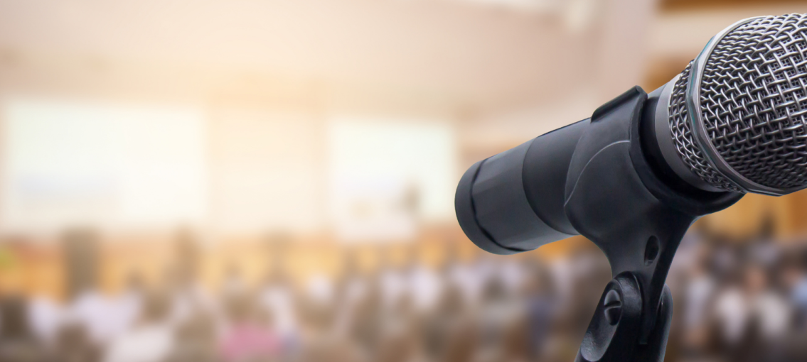 Close up of a microphone with blurred audience in the background